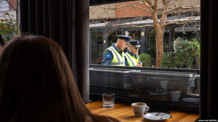 Dy policë duke ecur pranë një kafeneje në Vushtrri.