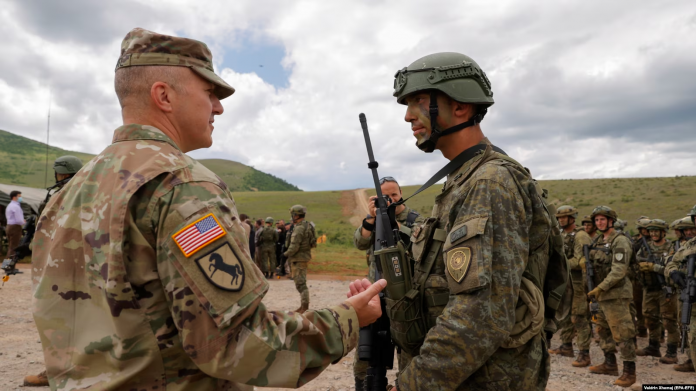 Një ushtar amerikan (majtas) bisedon me një ushtar të Forcës së Sigurisë së Kosovës (FSK), pas stërvitjes ushtarake “Defender Europe 21” në fshatin Devë, Kosovë, më 28 maj 2021.